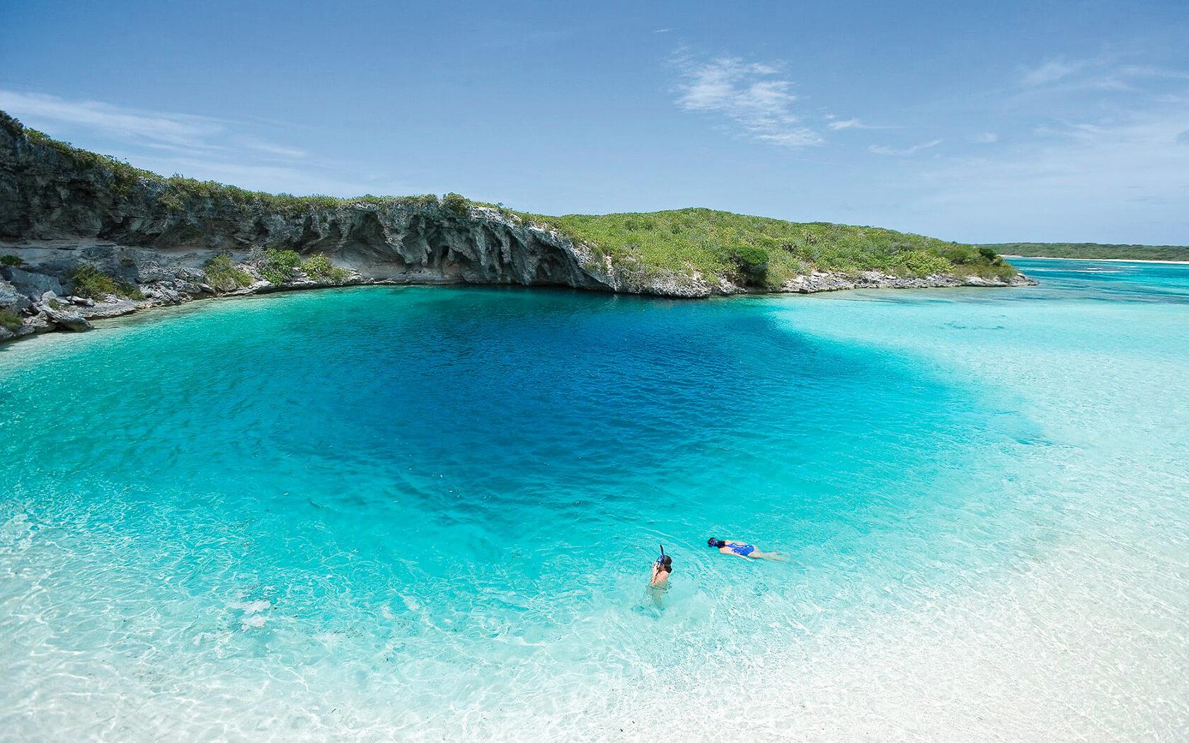 aerial view of two people swimming in a blue hole