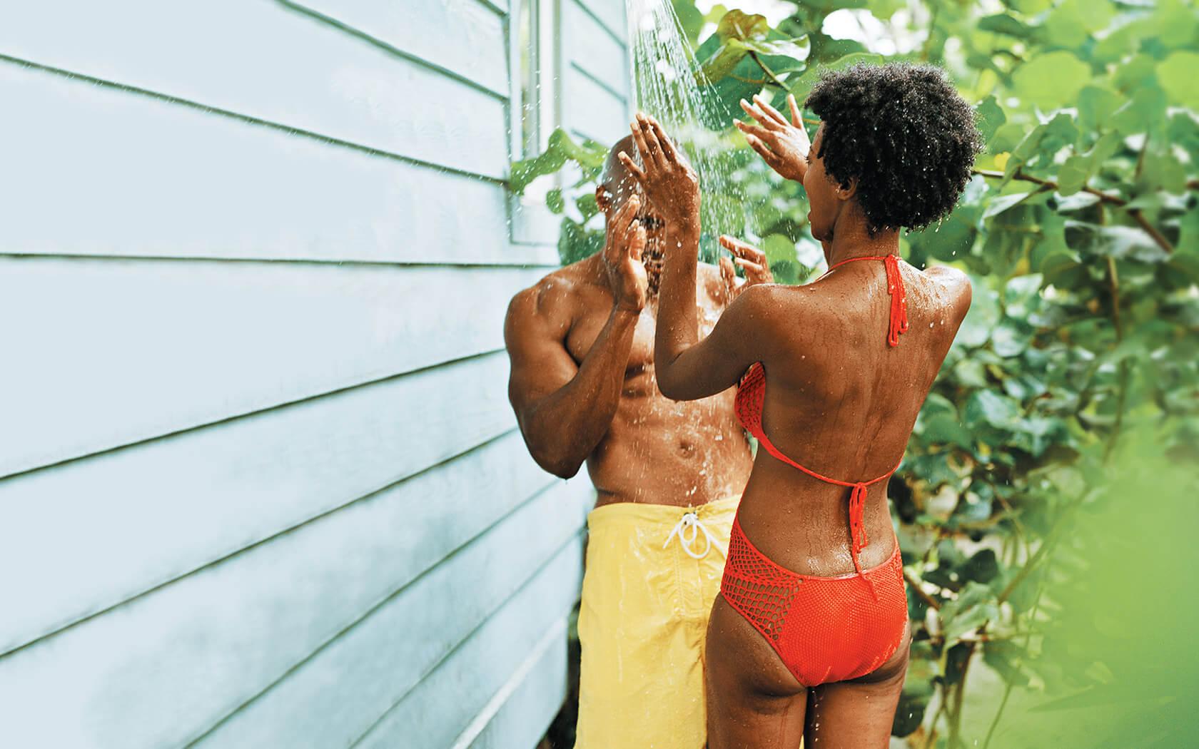 couple in bathing suits splashing in an outdoor shower area